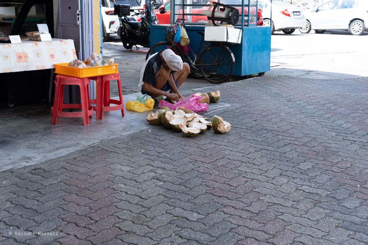 路上でココナッツを割る人